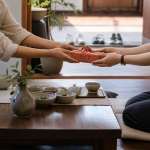 Two people exchanging a wrapped item with both hands in a home
